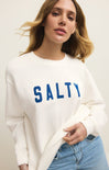 Woman wearing a white sweatshirt with 'SALTY' in blue text on a plain background
