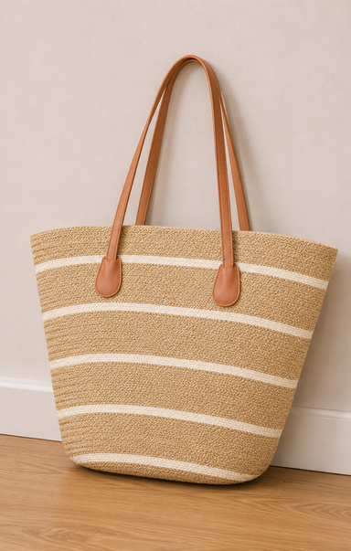 Woven tote bag with striped pattern and brown leather handles on a wooden floor.