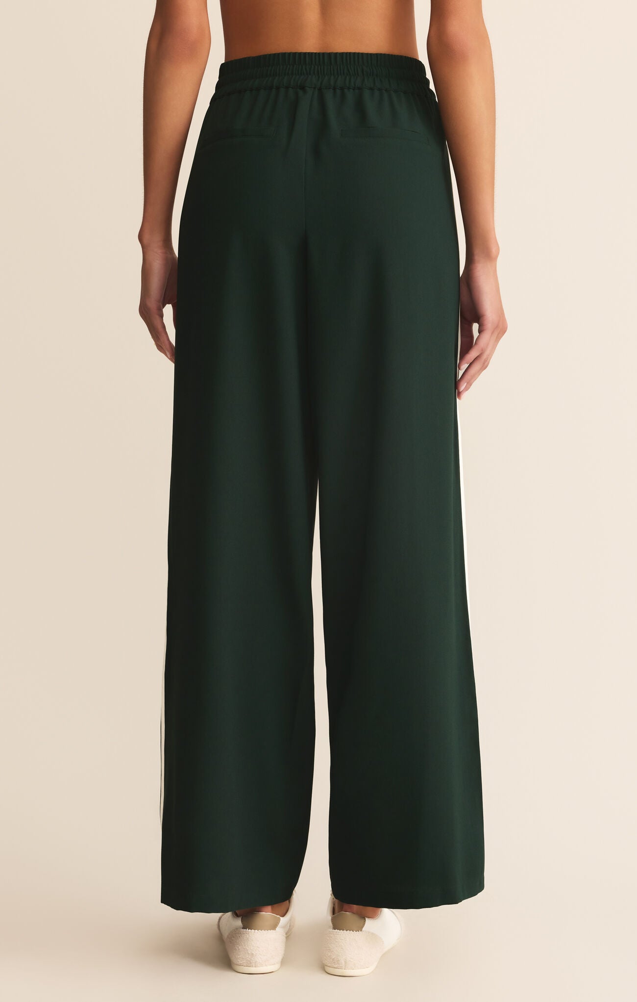 Dark green wide-leg pants worn by a person on a beige background