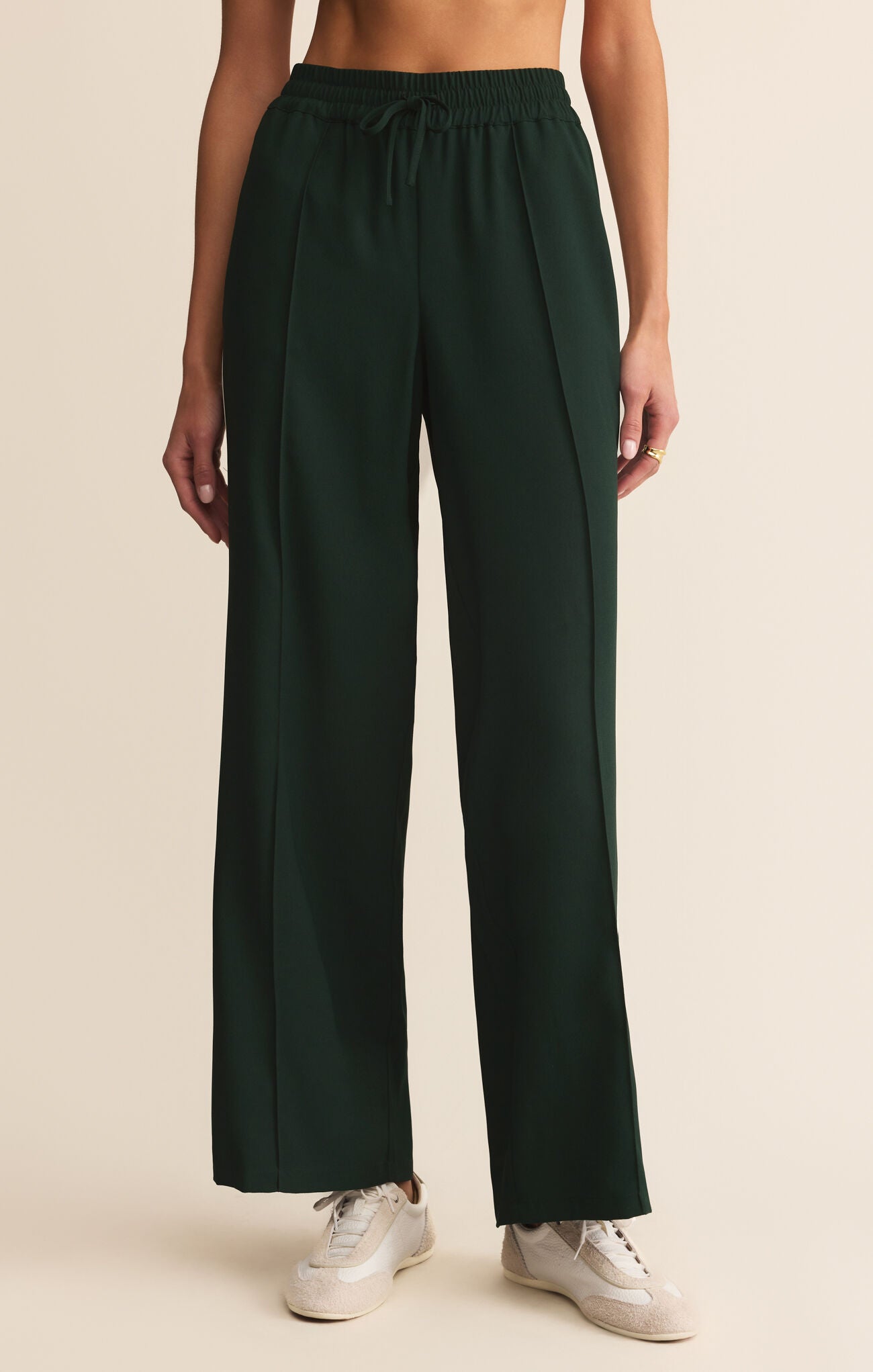 Dark green wide-leg pants worn by a person on a beige background