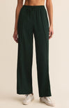 Dark green wide-leg pants worn by a person on a beige background