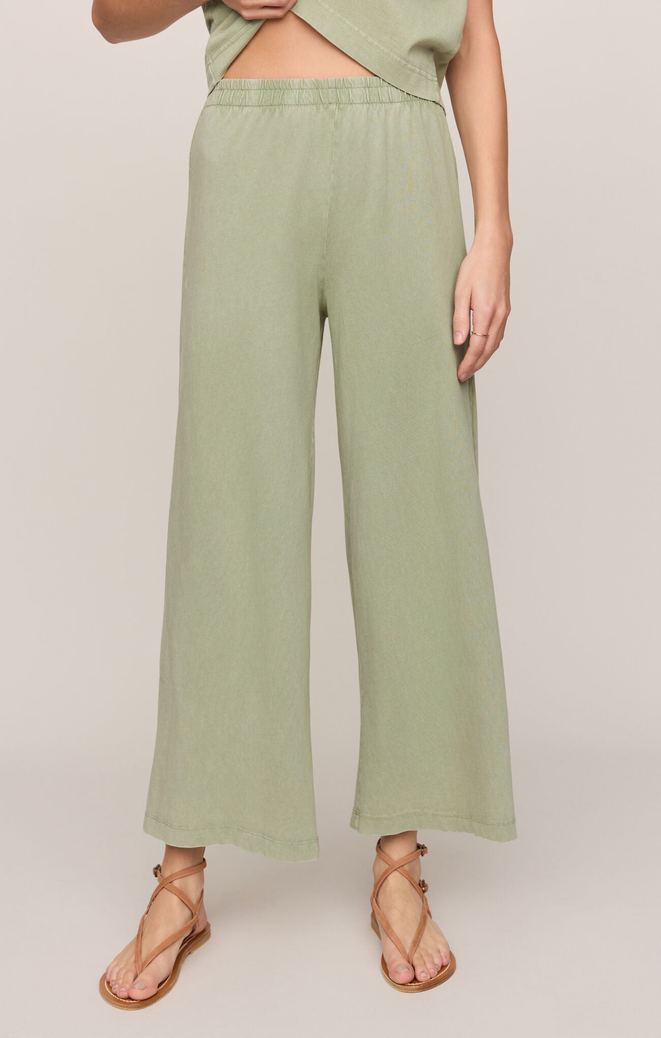 Person wearing light green wide-leg pants on a plain background