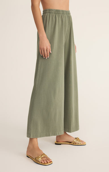 Person wearing a green wide-leg pants on a plain background