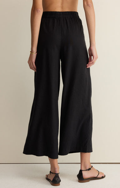 Person wearing black wide-leg pants on a plain background