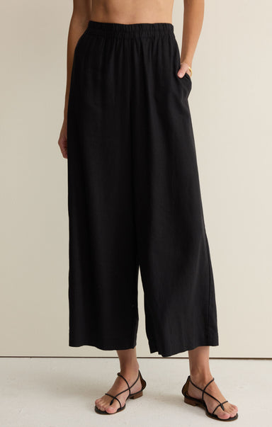 Person wearing black wide-leg pants on a plain background