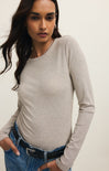 Woman wearing a gray long-sleeve top and blue jeans against a white background