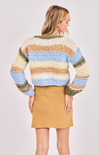 Woman wearing a colorful striped sweater and beige skirt on a white background