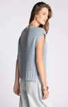Woman wearing a light blue knitted vest against a white background