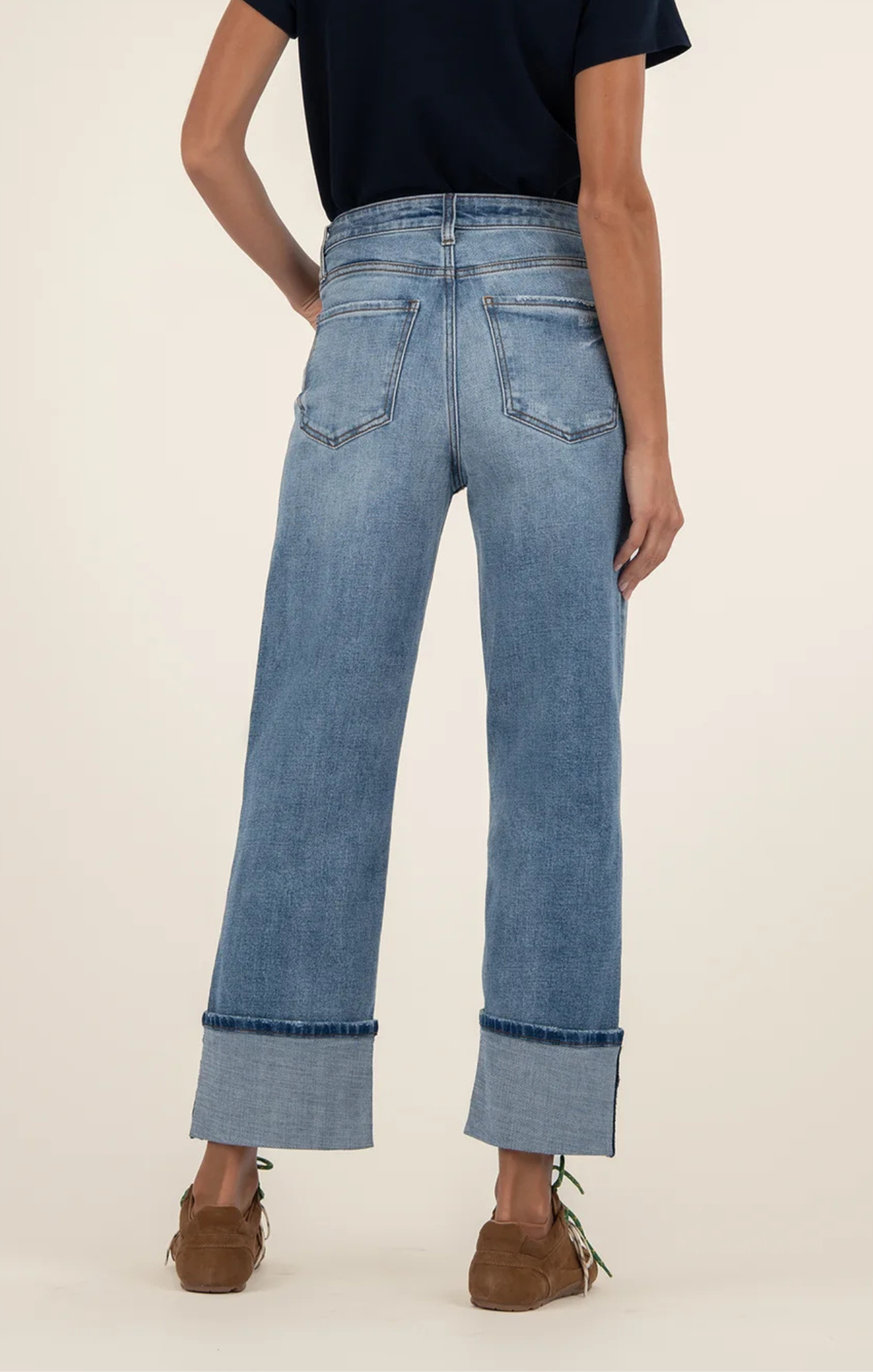 Person wearing light blue jeans with a plain background