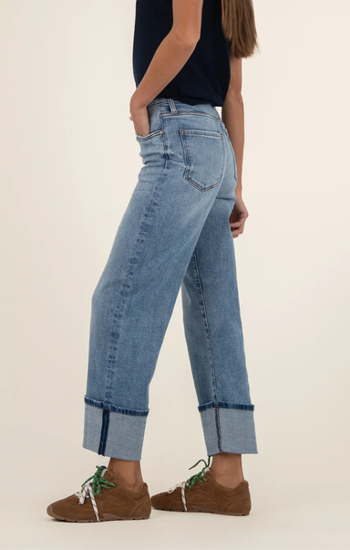 Person wearing light blue jeans and brown shoes on a plain background