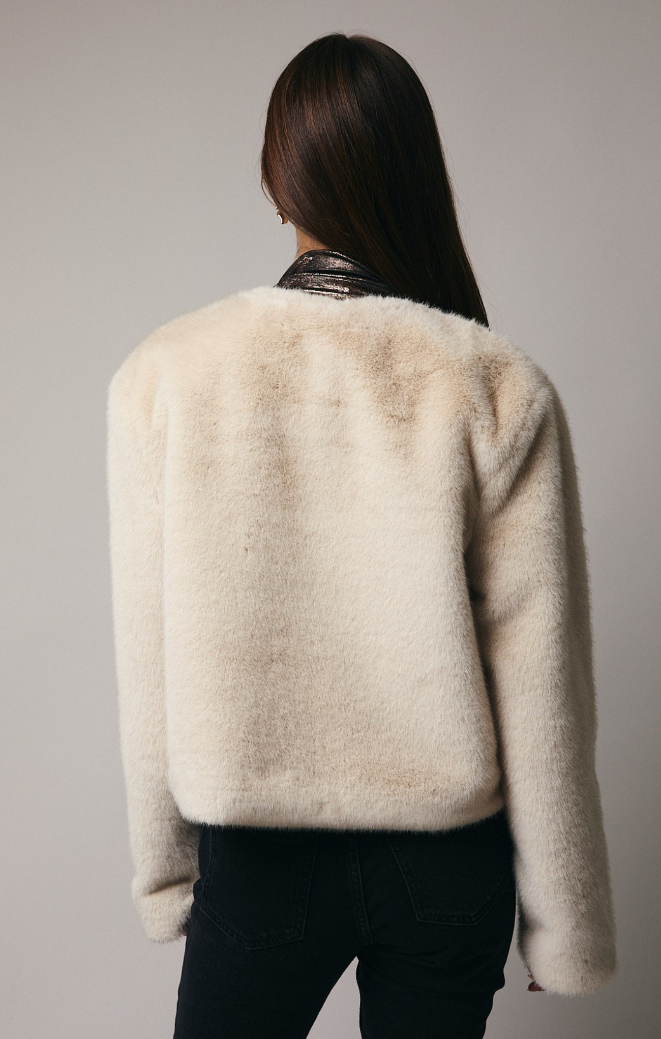 Person wearing a fluffy beige jacket against a plain background