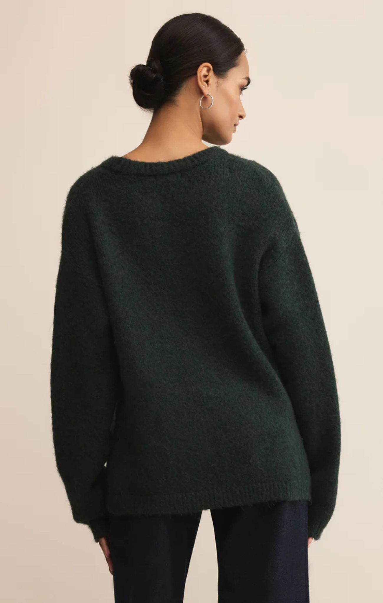 Person wearing a dark green sweater against a beige background