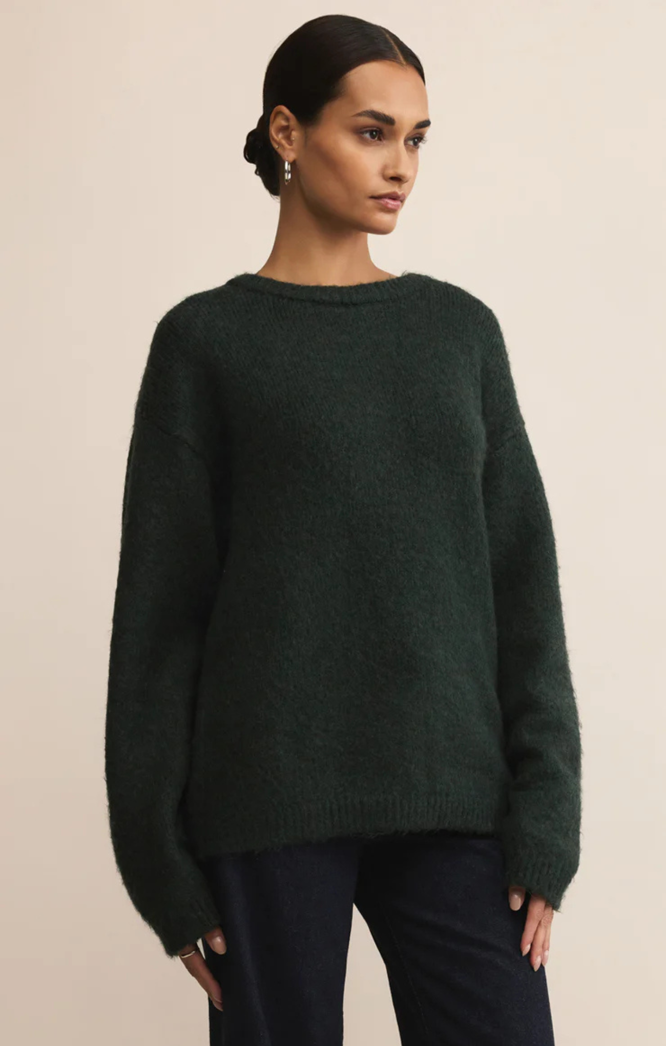 Woman wearing a dark green sweater against a beige background