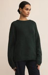 Woman wearing a dark green sweater against a beige background