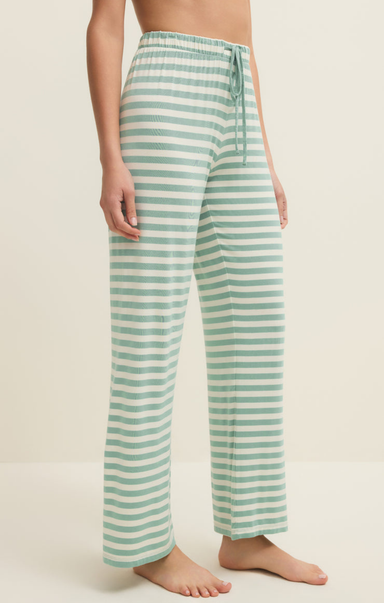 Green and white striped pants worn by a person on a beige background