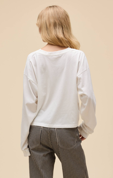 Person wearing a white long-sleeve top and striped pants on a beige background