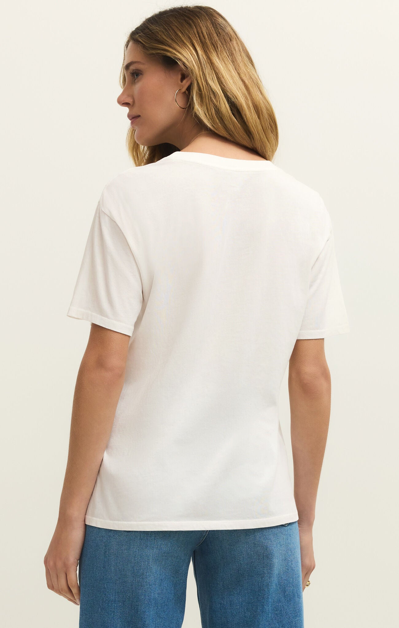Woman wearing a white t-shirt and blue jeans on a plain background