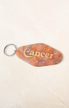 Keychain with 'Cancer' text on a beige background