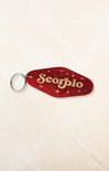 Red 'Scorpio' keychain on a beige background