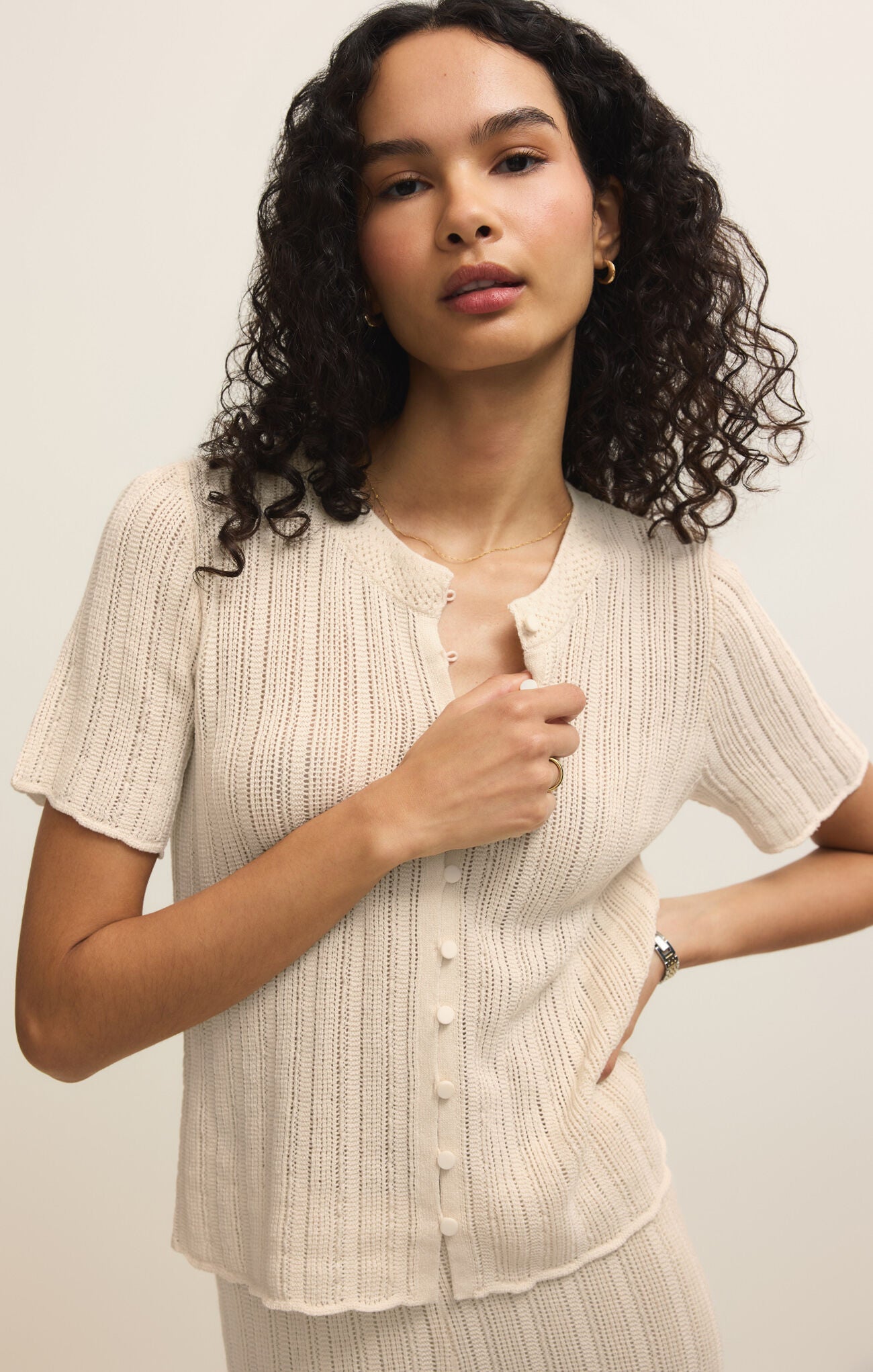 Woman wearing a beige ribbed blouse against a plain background
