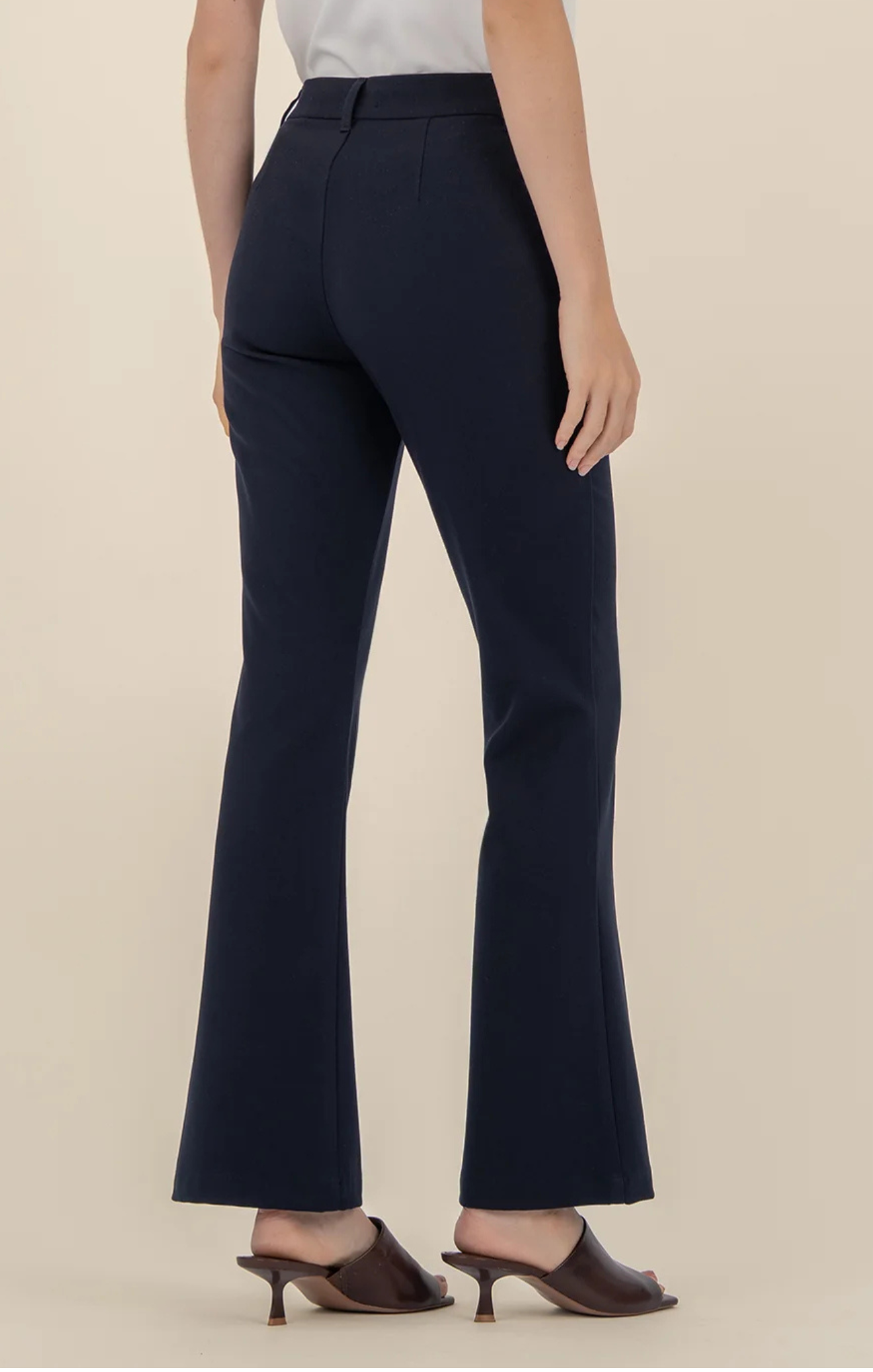 Navy blue flared pants worn by a person on a beige background