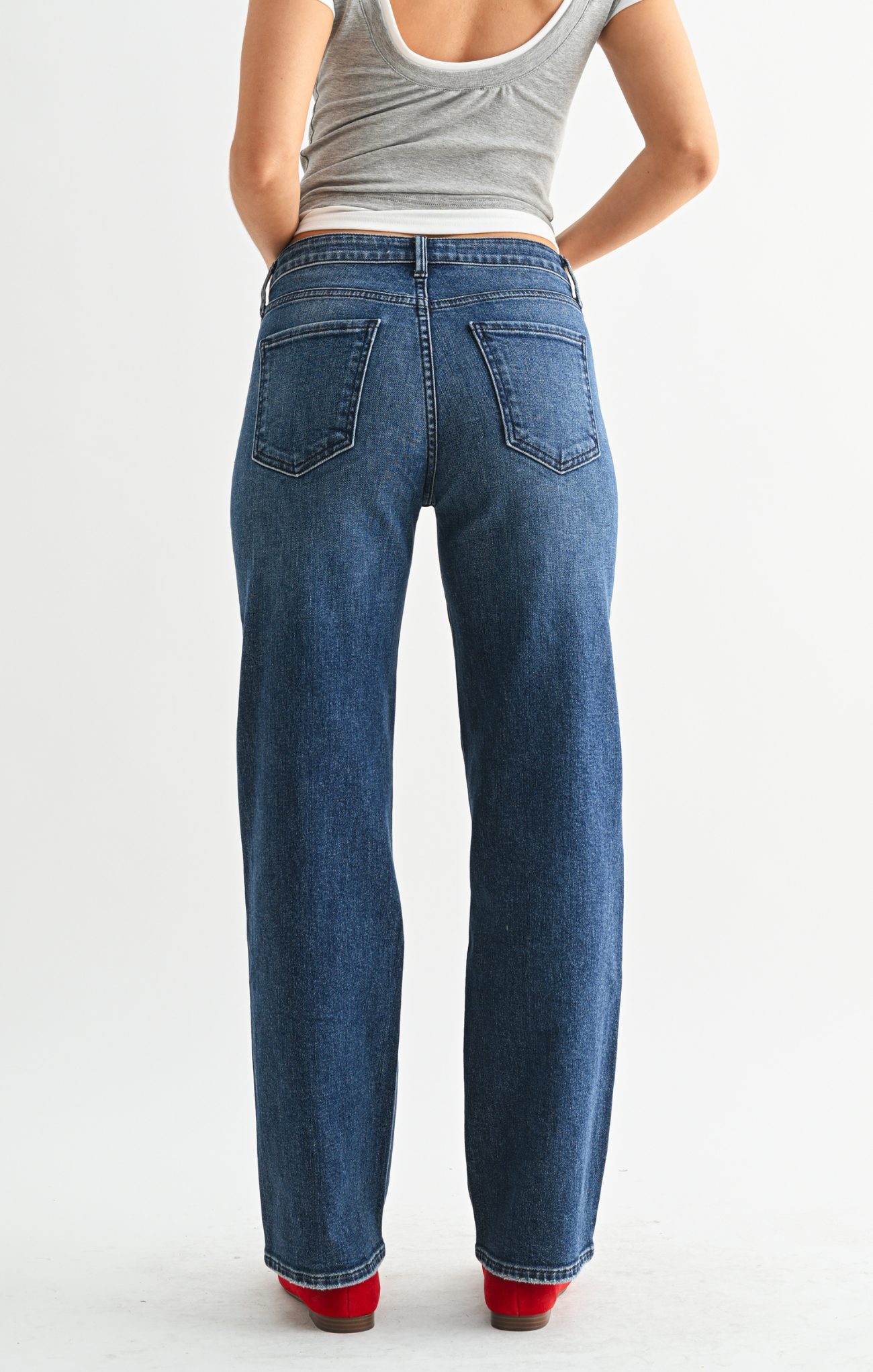 Person wearing blue jeans and a gray tank top on a white background