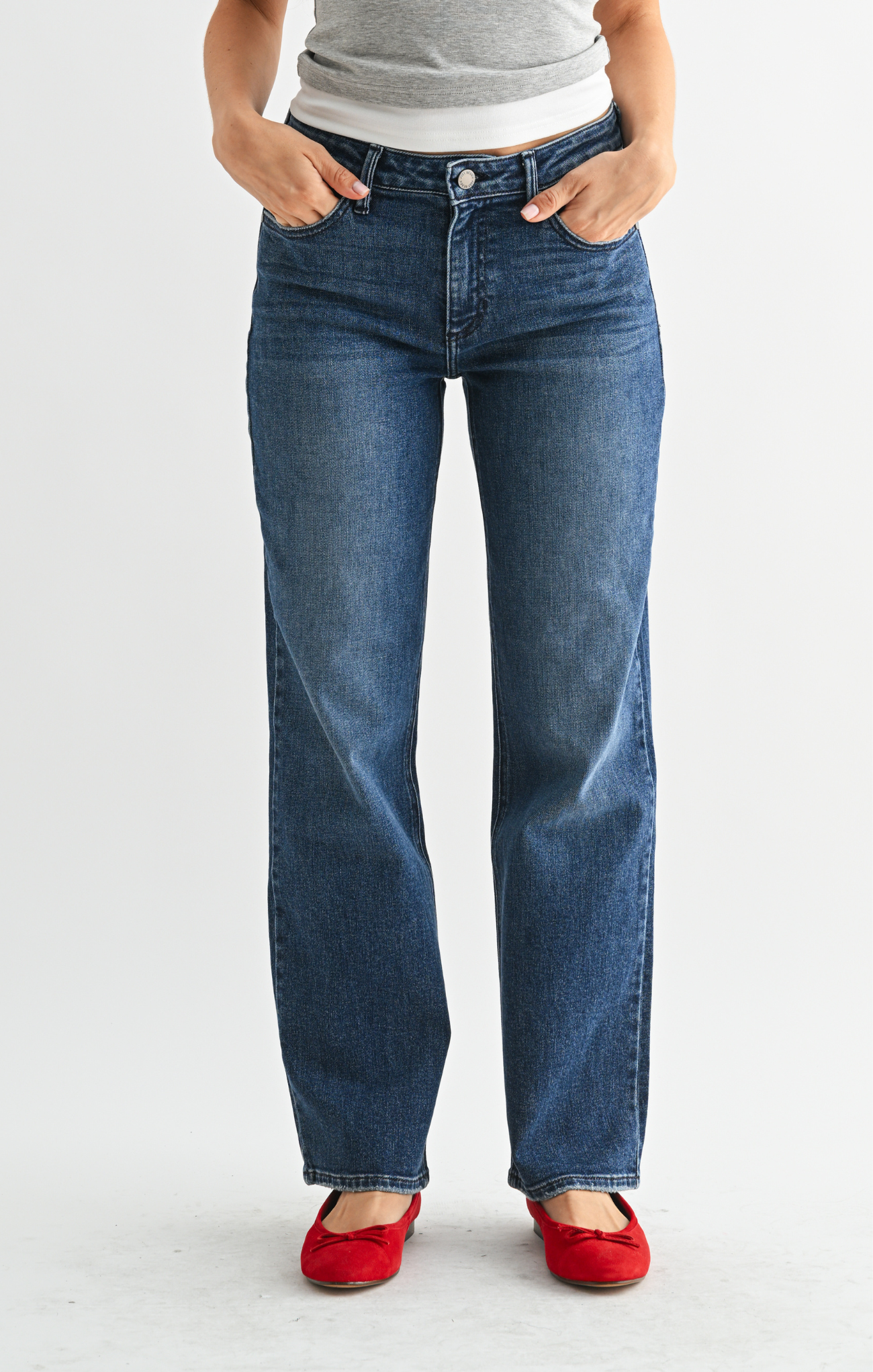 Person wearing blue jeans and red shoes on a white background