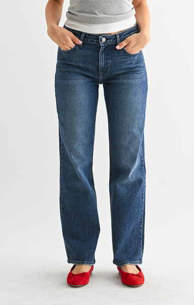 Person wearing blue jeans and red shoes on a white background