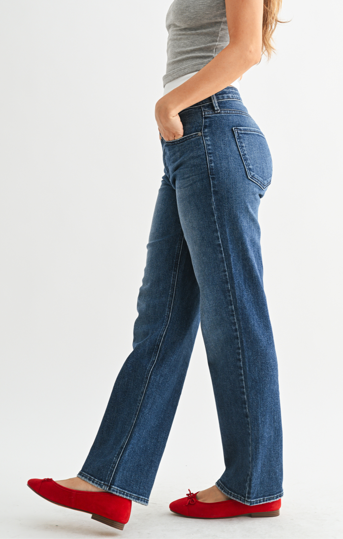 Person wearing blue jeans and red shoes on a white background