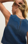 Woman wearing a blue denim top with a plain background