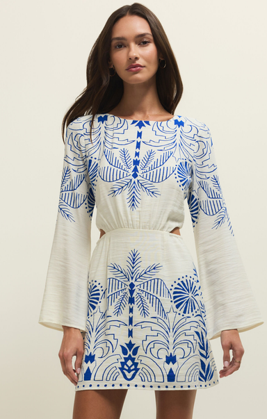 Woman wearing a white dress with blue floral patterns against a beige background