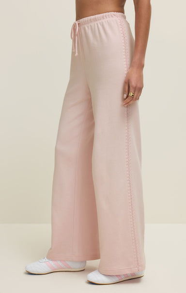 Person wearing light pink pants on a beige background