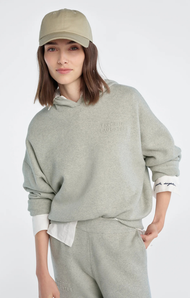 Person wearing a gray hoodie and pants with a beige cap on a white background