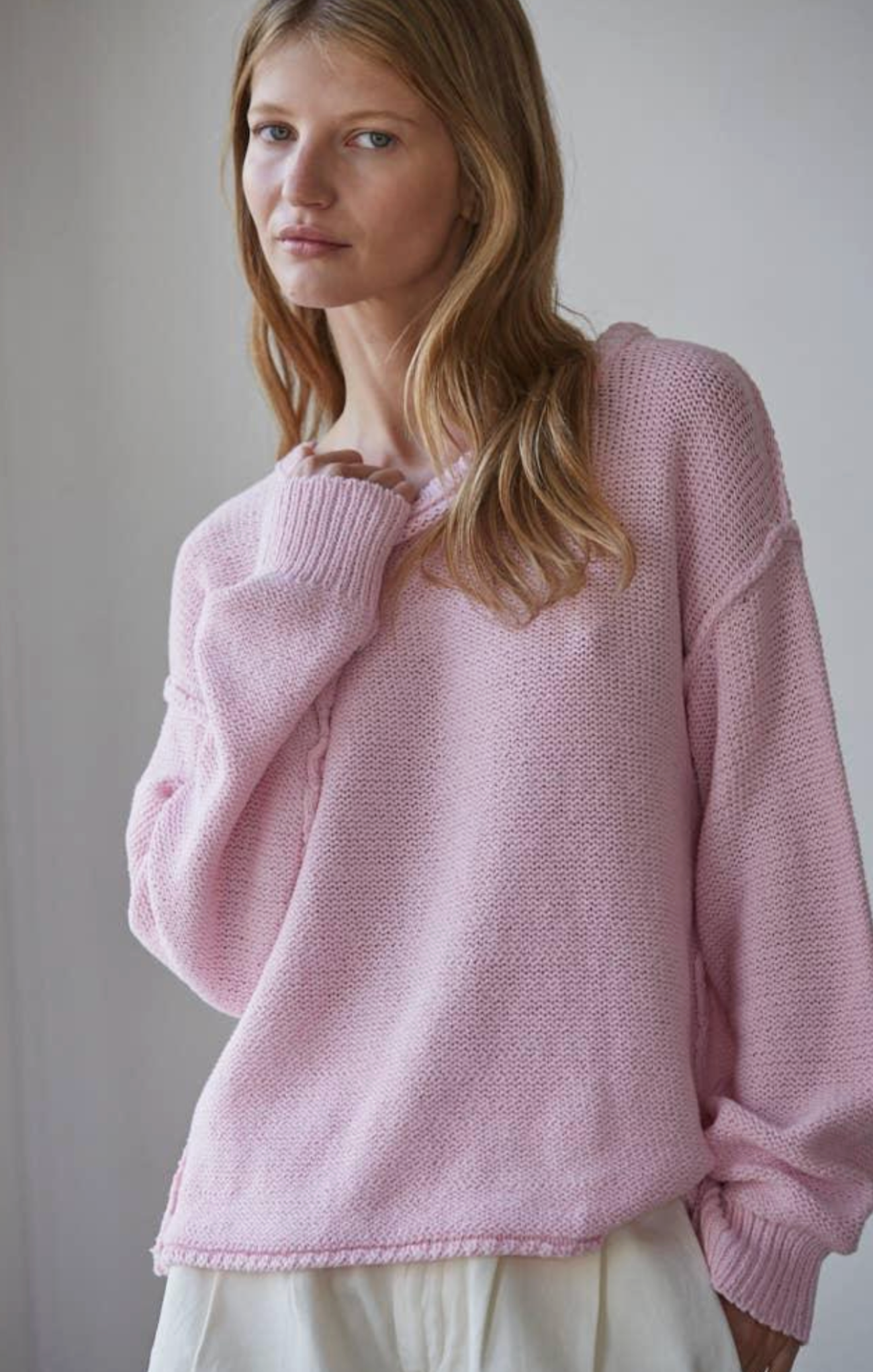 Woman wearing a pink knitted sweater against a plain background