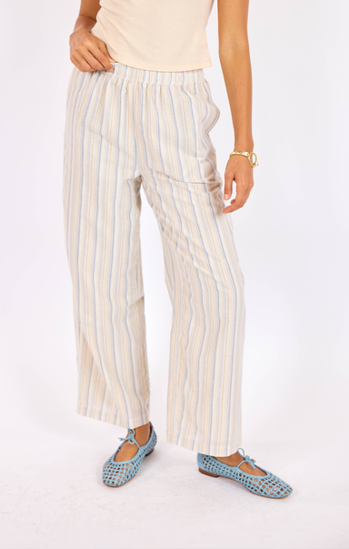 Person wearing striped pants and blue flats on a white background