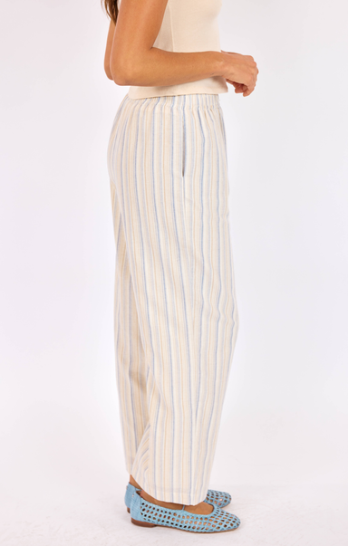 Woman wearing striped pants and blue flats on a white background