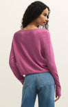 Woman wearing a pink sweater and blue jeans on a plain background