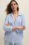 Woman wearing a light blue striped shirt against a plain background