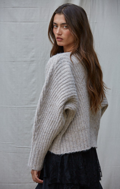 Woman wearing a light gray sweater against a plain background