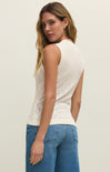 Woman wearing a white sleeveless top and blue jeans against a plain background