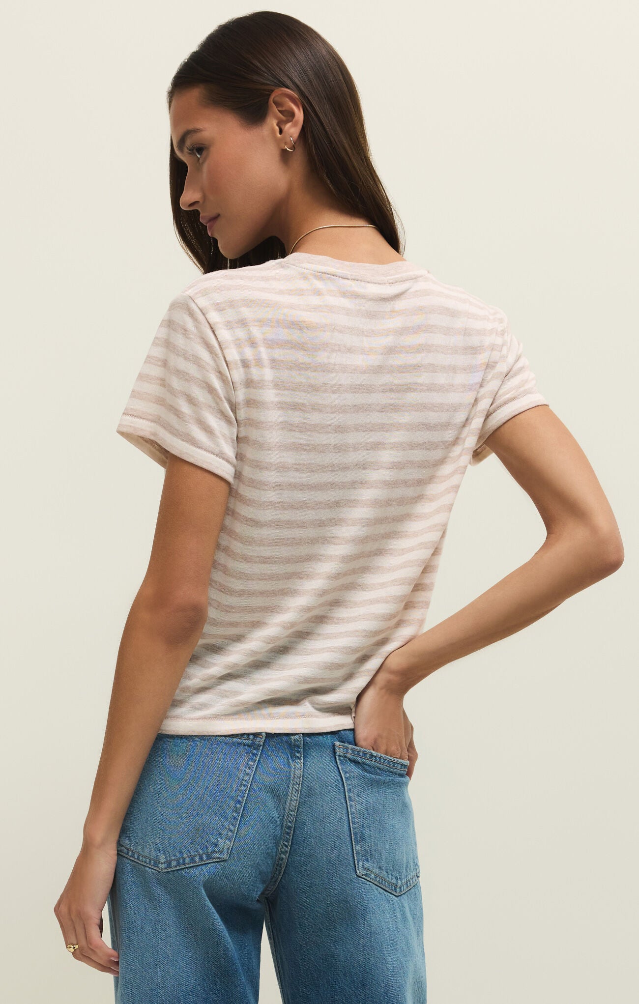Woman wearing a striped t-shirt and blue jeans against a plain background