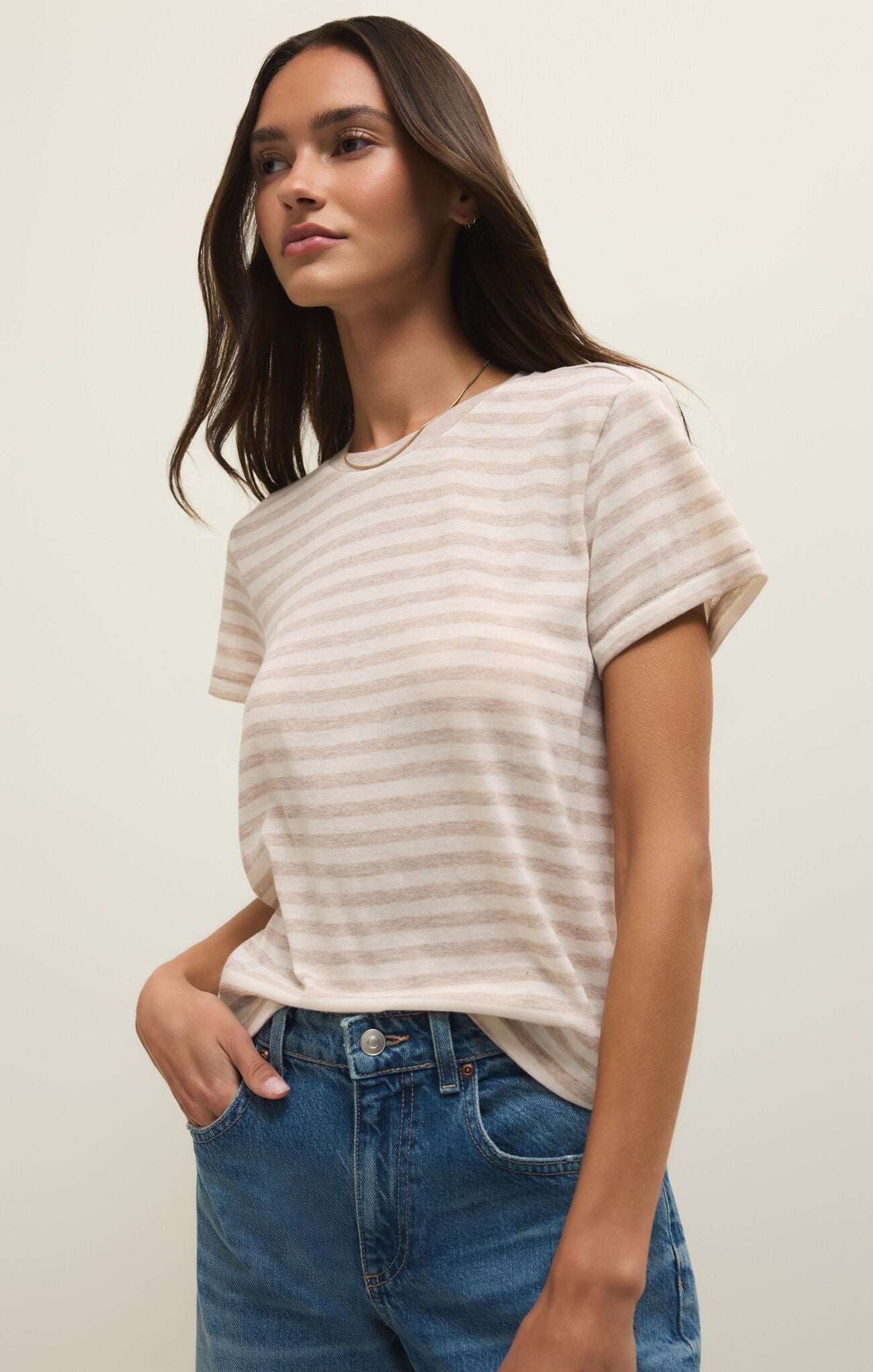 Woman wearing a striped shirt and jeans against a plain background