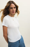 Woman wearing a white t-shirt and blue jeans against a plain background