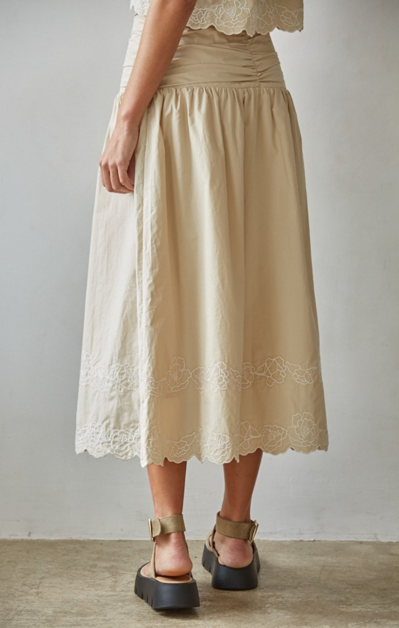 Beige skirt with lace details worn by a person on a plain background