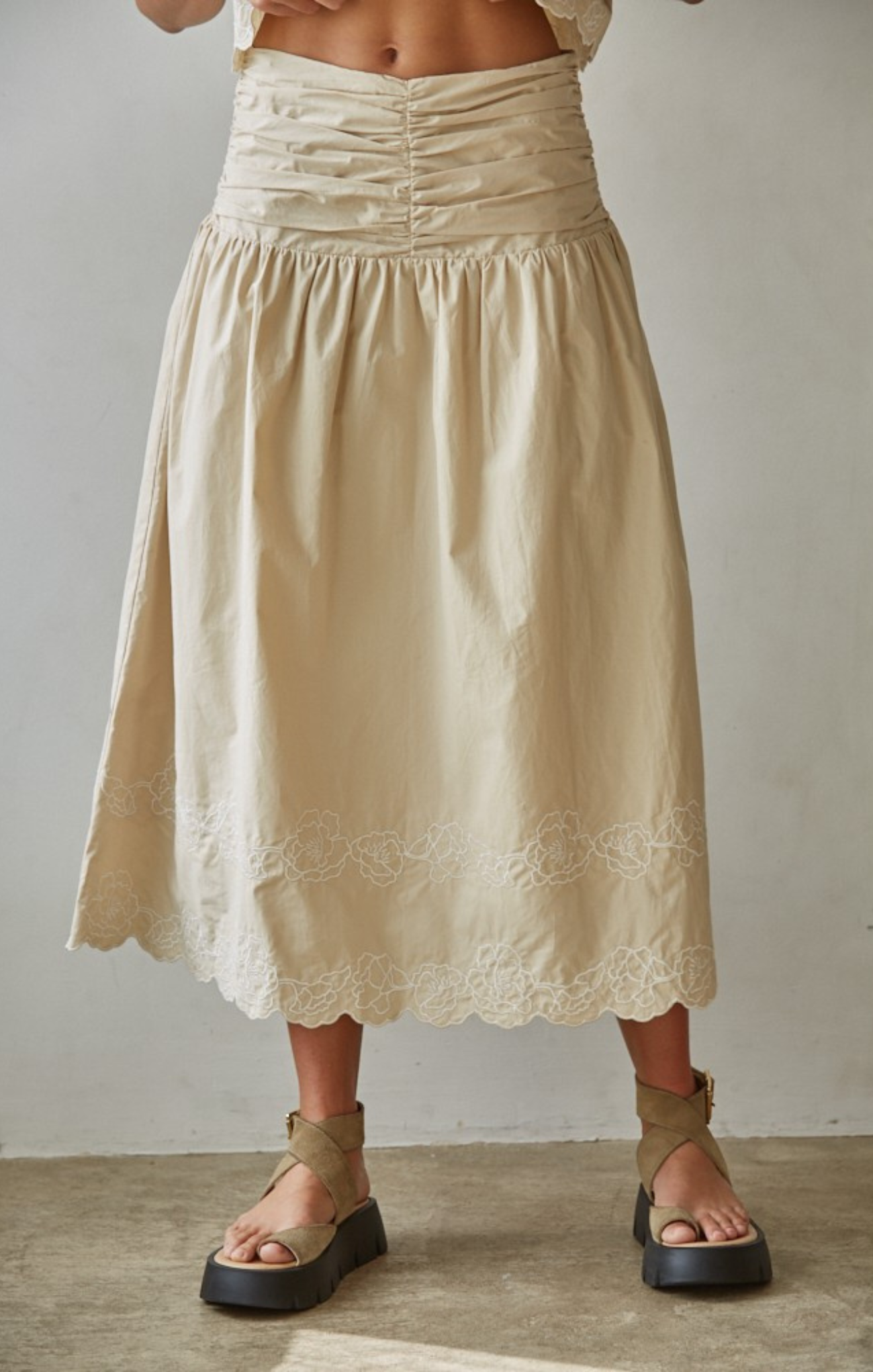 Beige skirt with lace details worn by a person on a plain background
