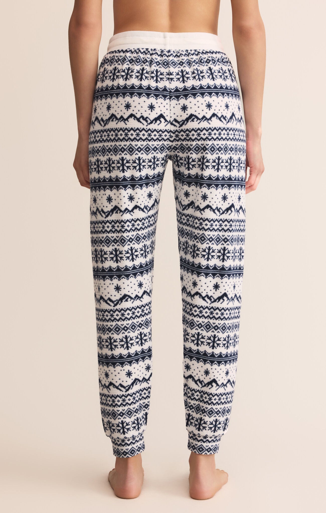 Patterned pajama pants worn by a person on a beige background
