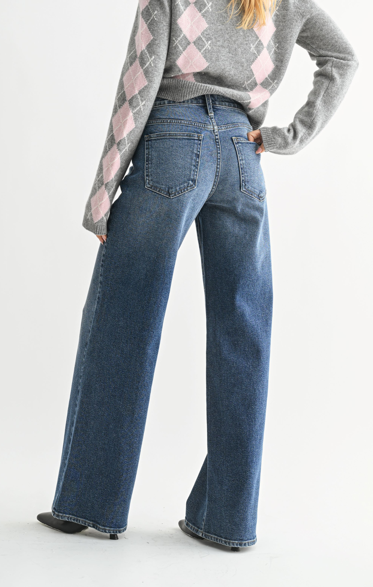 Person wearing blue jeans and a patterned sweater on a white background