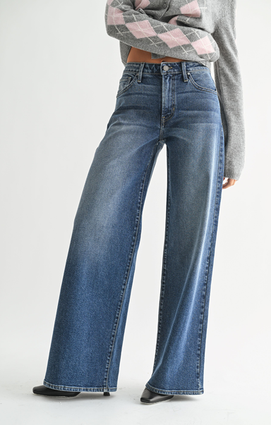 Person wearing blue wide-leg jeans and a patterned sweater on a white background