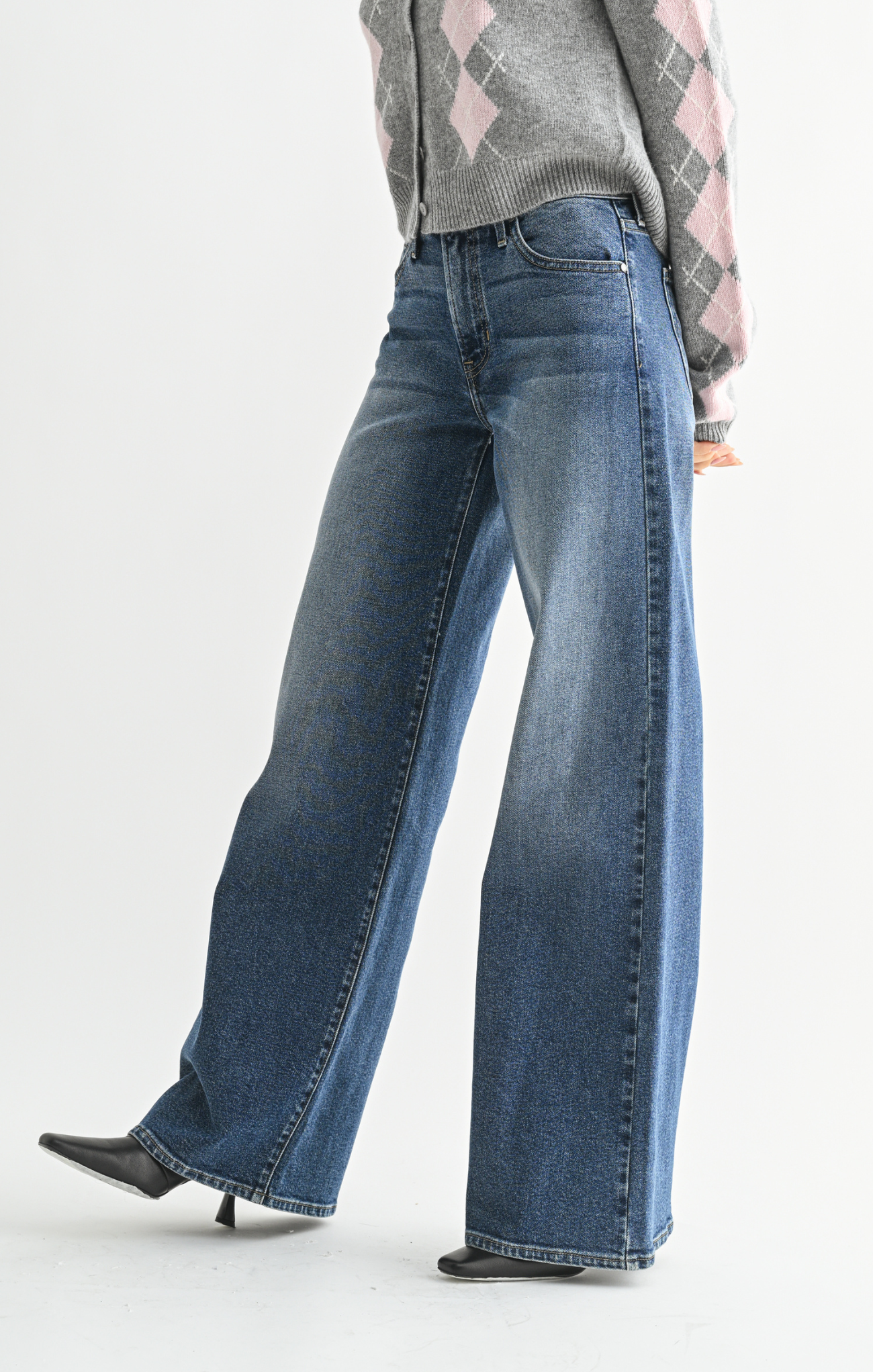 Person wearing blue jeans and a patterned sweater on a white background