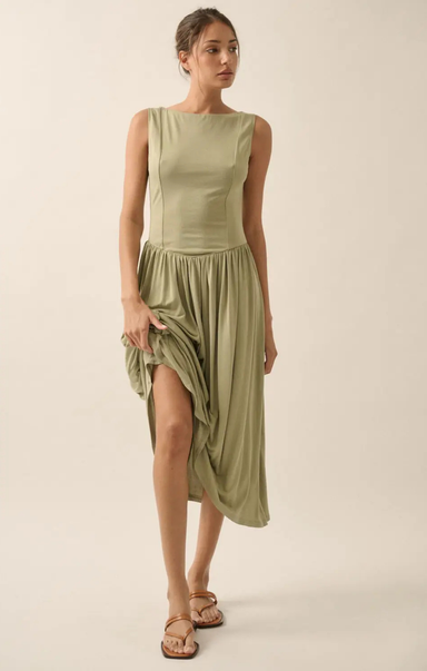 Woman wearing a green dress with a slit on a beige background